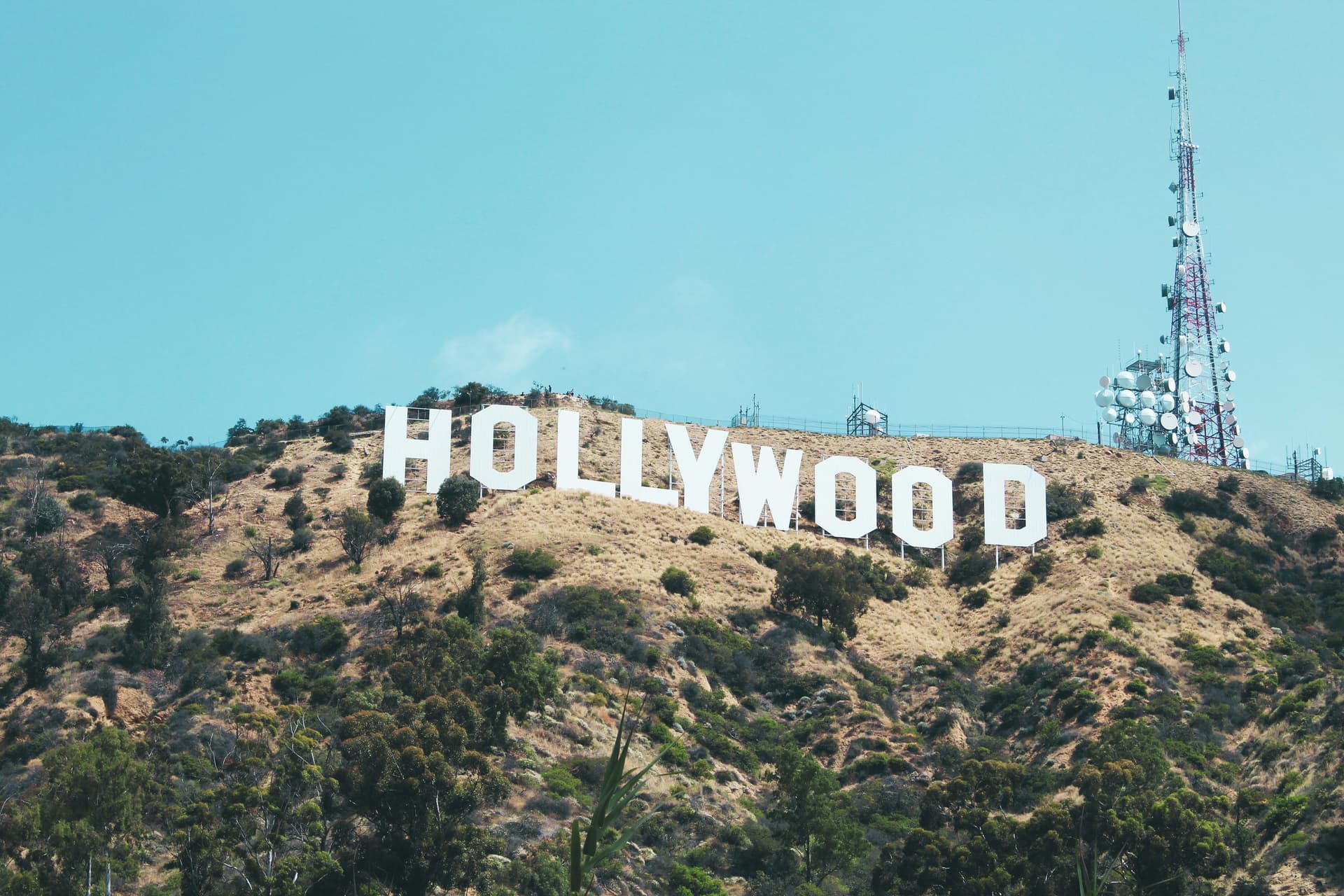 Famous Hollywood sign on a hillside with clear blue sky and communication towers.